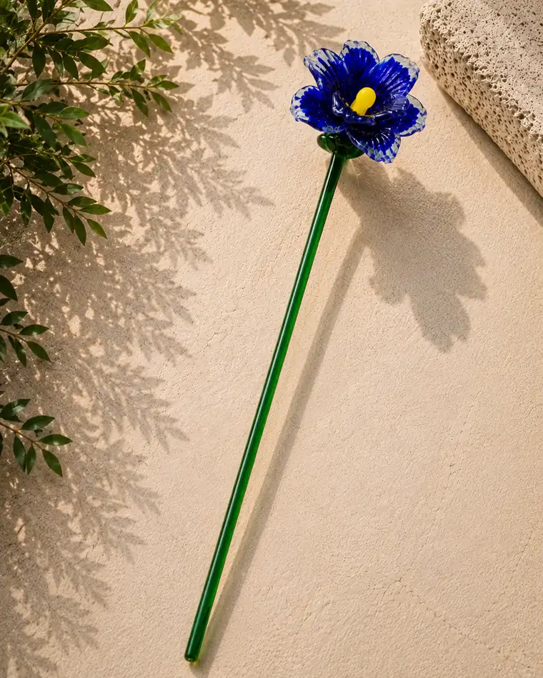 A dark blue glass flower with delicately patterned petals and a yellow centre.