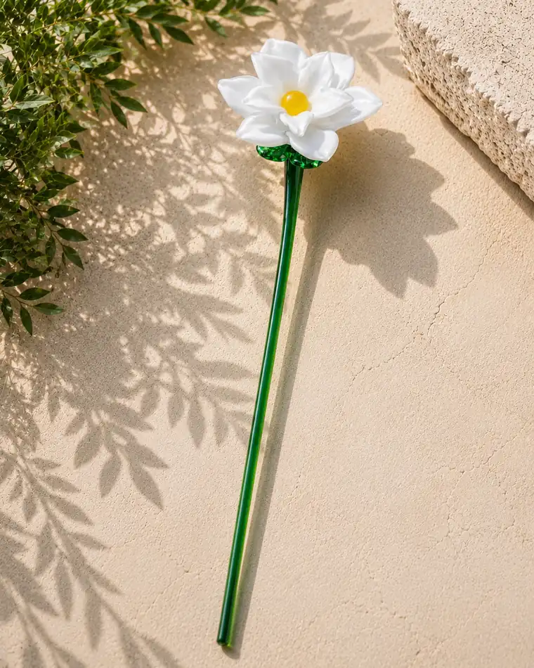 A white glass Camellia with a yellow centre on a green glass stem.