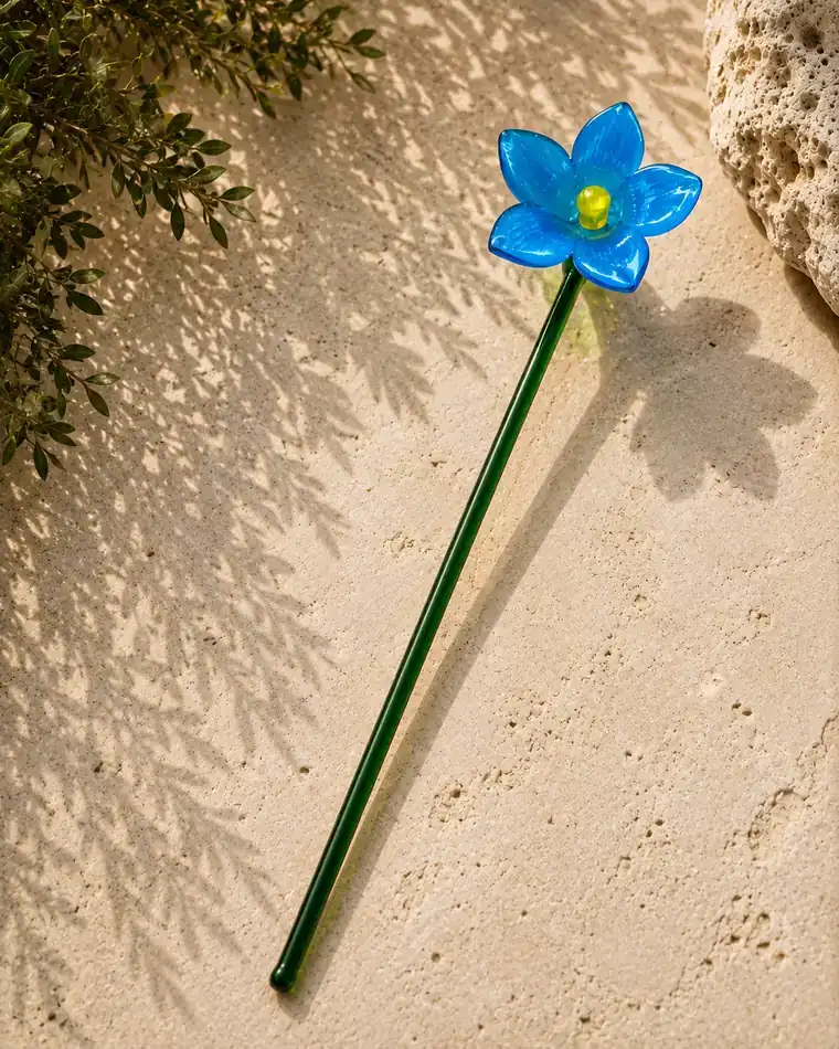 A light blue glass flower with five petals and a yellow centre.